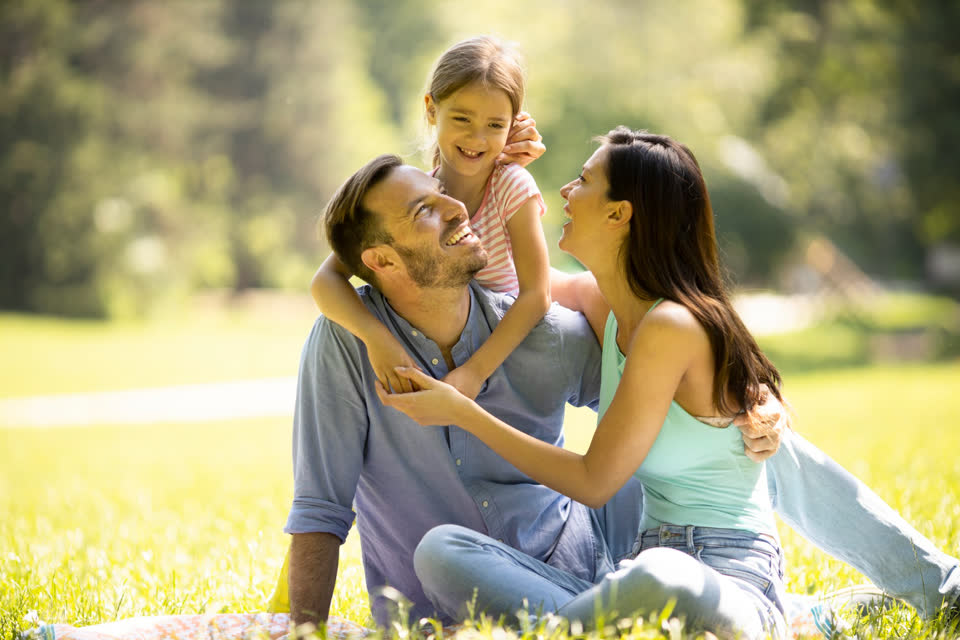 Family outdoors, parents and daughter smiling